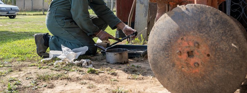 Monteur werkt buiten aan een landbouwwerktuig op een erf.